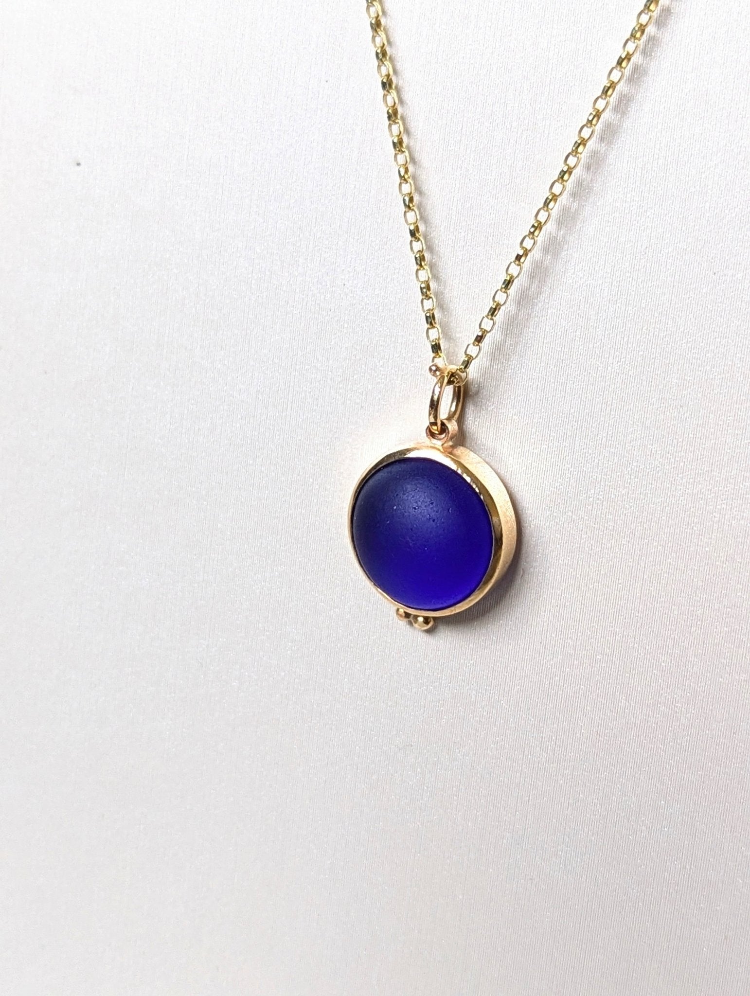 9ct Gold Cobalt Blue Sea Glass Necklace. Close-up of a 9 carat gold necklace with a cobalt blue sea glass pendant, set in a  gold bezel with a delicate gold chain by Booblinka Jewellery