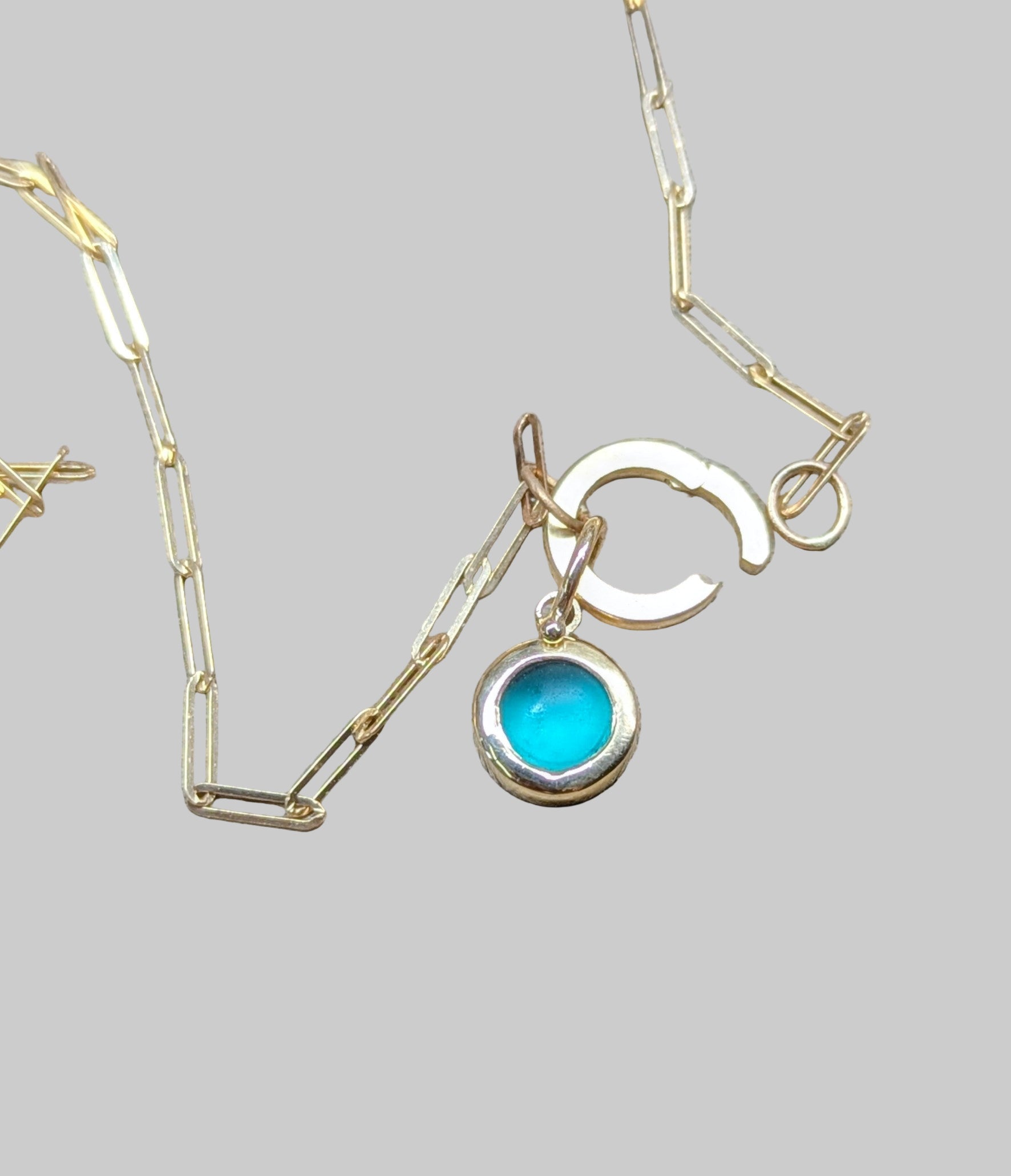 Gold necklace with a blue pendant on a wooden surface