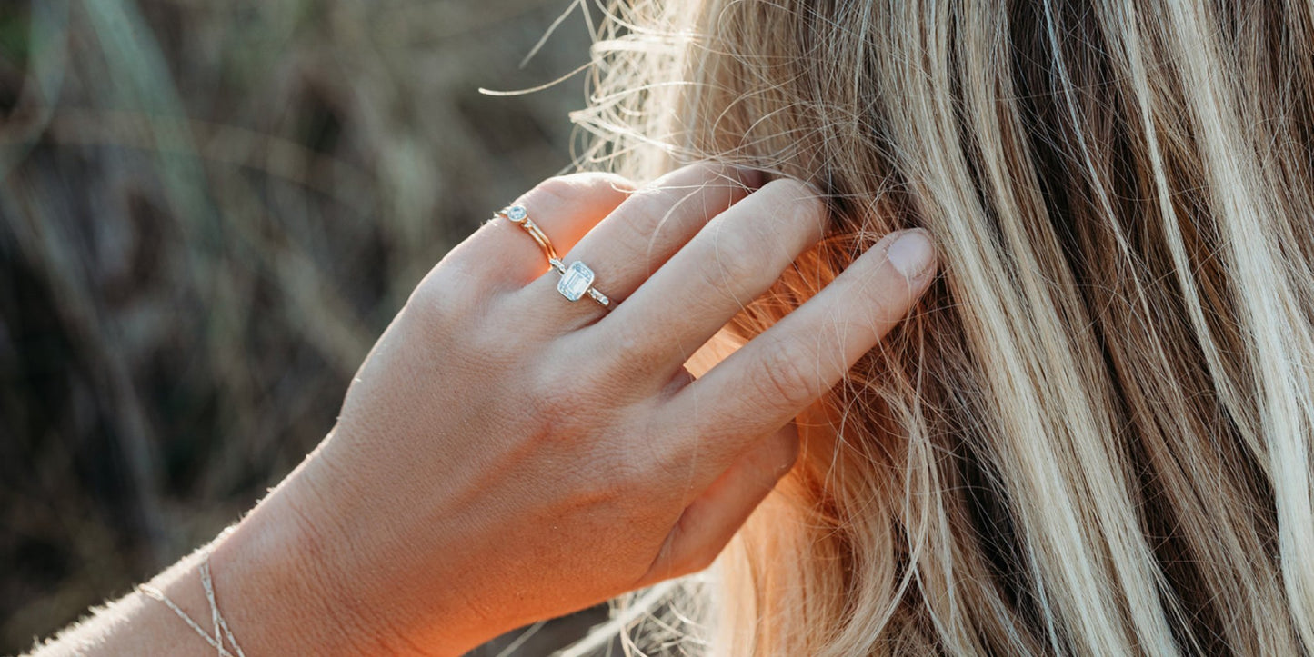 Emerald-Cut Moissanite and Gold Accent Ring from DEI Collection on hand running through blond hair by Booblinka jewellery