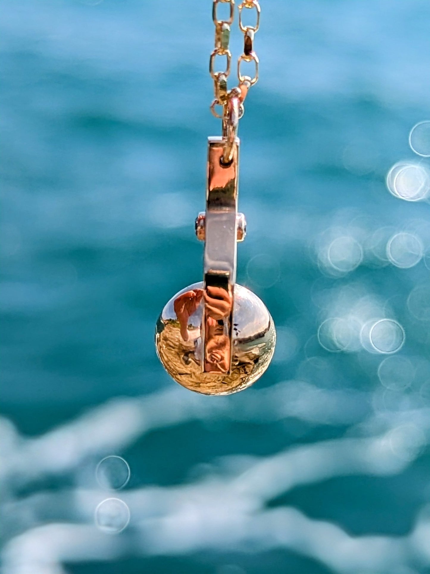 Side detail of Gold Spinning Necklace with Ocean Diamonds with the sea in background. Made by Booblinka Jewellery