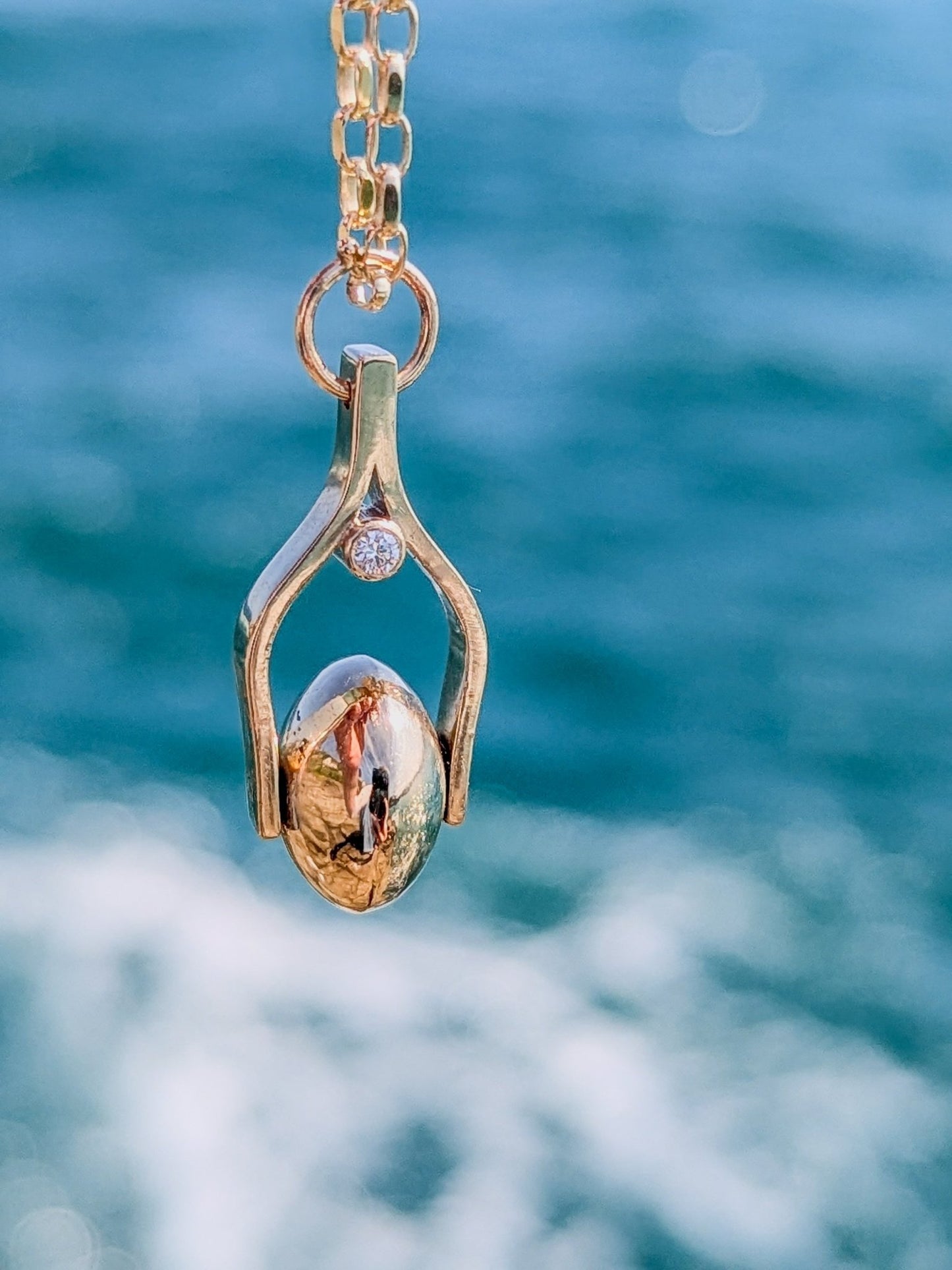 Gold Spinning Necklace with Ocean Diamonds  with the sea in the background. Made by Booblinka Jewellery.