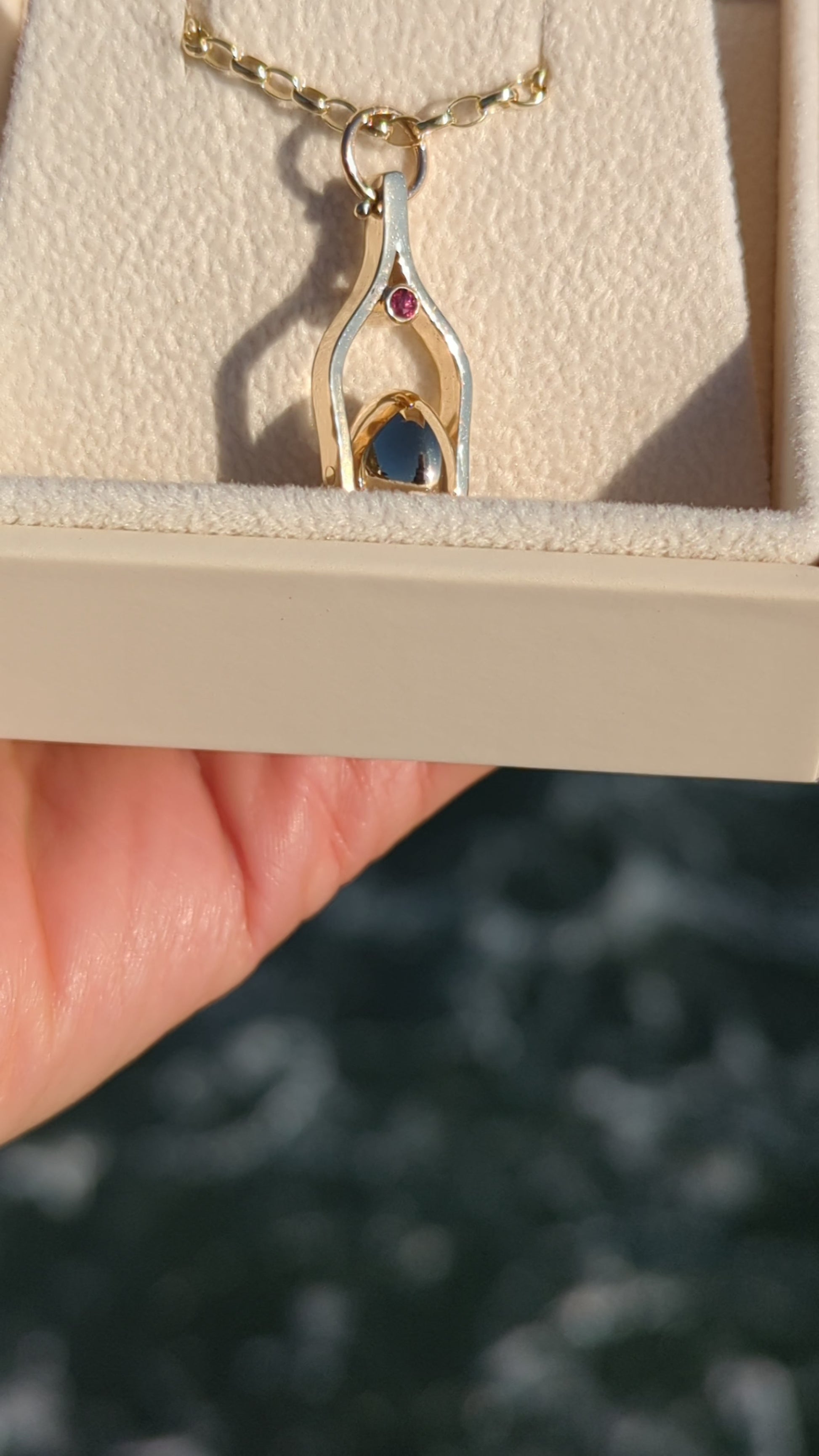 video of Spinning Moon Necklace made of solid 9 Carat Gold with two Pink Tourmalines by Booblinka Jewellery in an ivory jewellery box above shimmering ocean