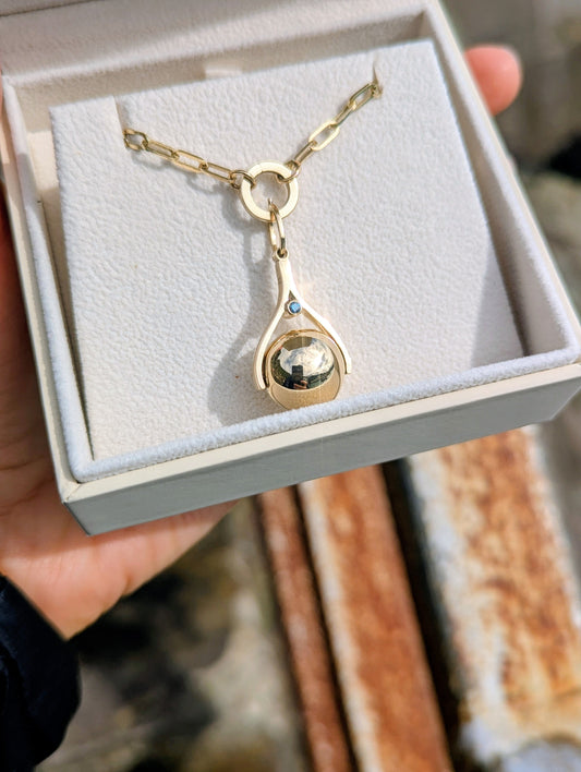 handmade spinning gold memorial necklace holding ashes in a jewellery box held in hand made by Booblinka Jewellery