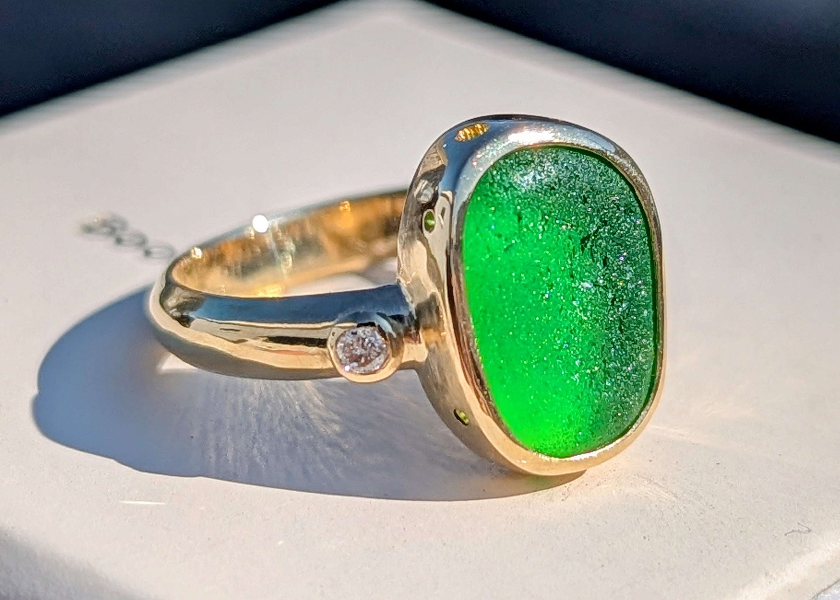 18 carat Gold ring with a green sea glass and a diamond on an ivory jewellery box made by Booblinka Jewellery