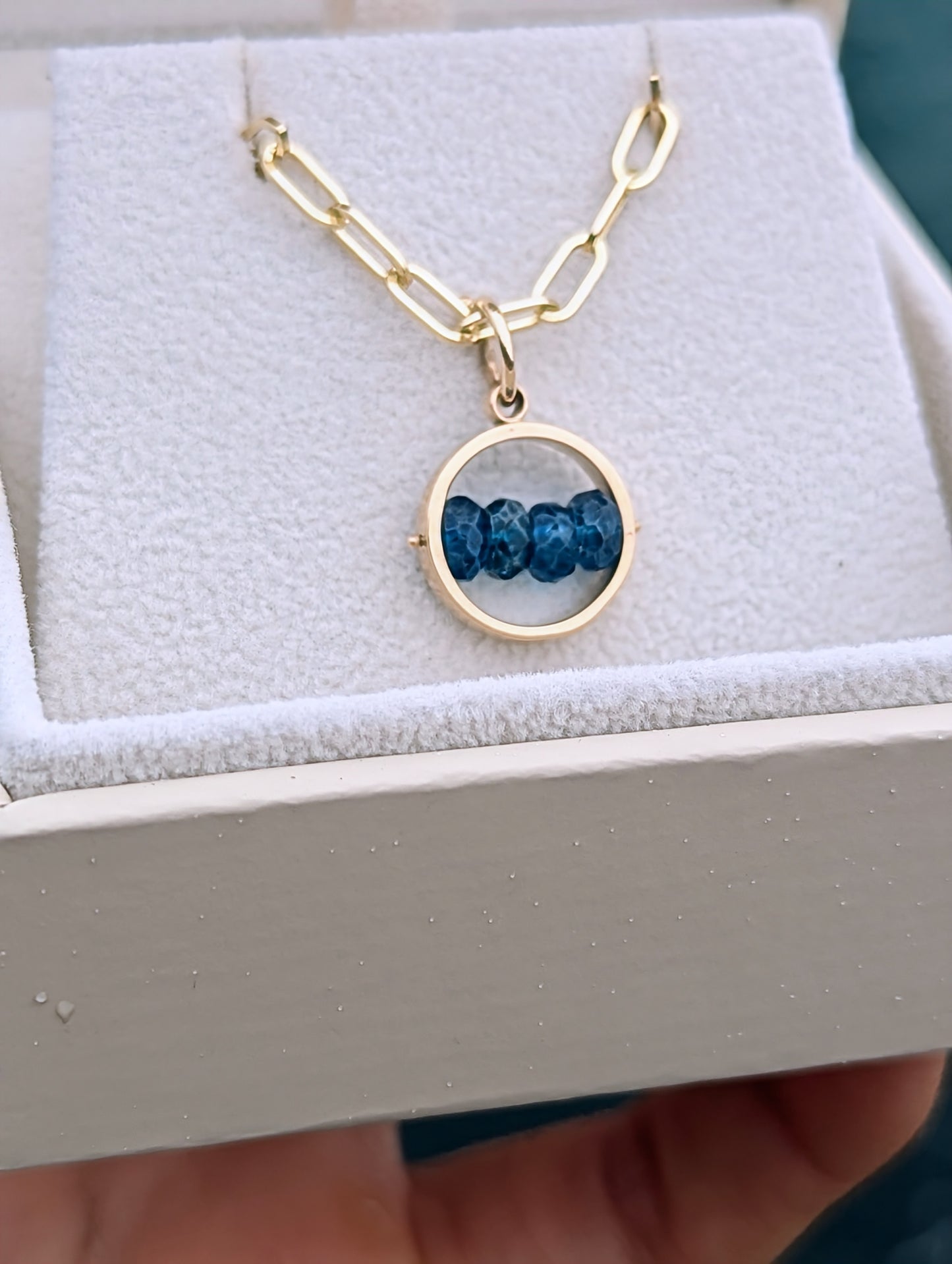 9ct gold blue topaz HALO pendant with four deep blue gemstones, shown on its solid gold paperclip chain in a jewellery box.