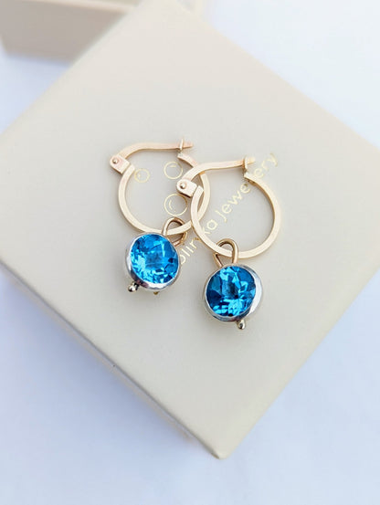 9ct gold hoop earrings with removable blue topaz charms on an ivory jewellery box handmade by Booblinka Jewellery