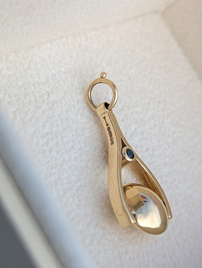 Detail of a hallmark on a 9c Gold spinning pendant with a teal sapphire on a white background made by Booblinka Jewellery.