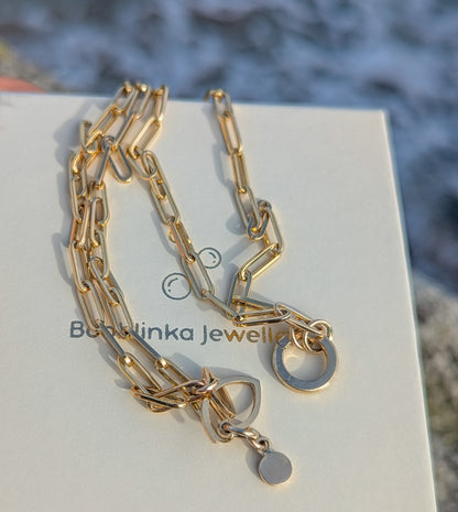 Gold paperclip chain necklace on a branded jewellery box with a blurred natural background made by Booblinka Jewellery.
