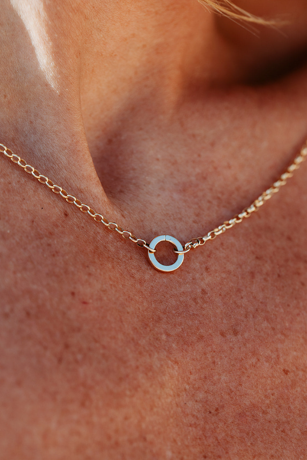 Gold necklace with a circular pendant on a person's neck made by Booblinka Jewellery