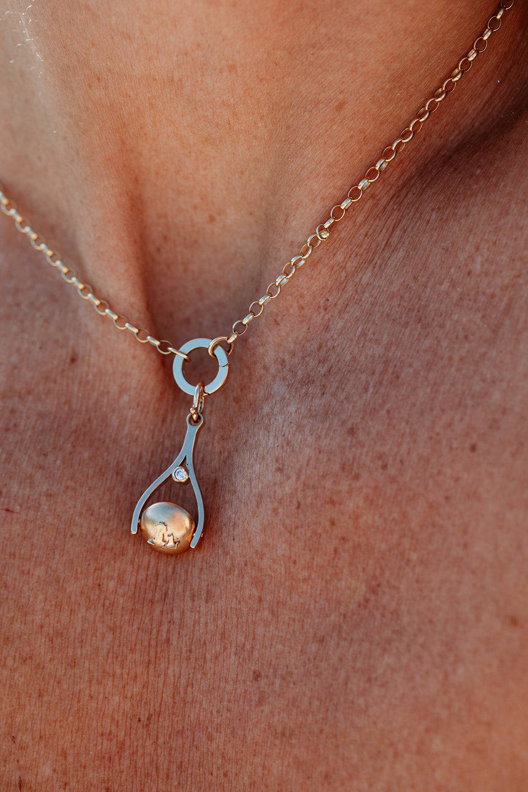 Gold necklace with a spinning pendant on a person's neck
