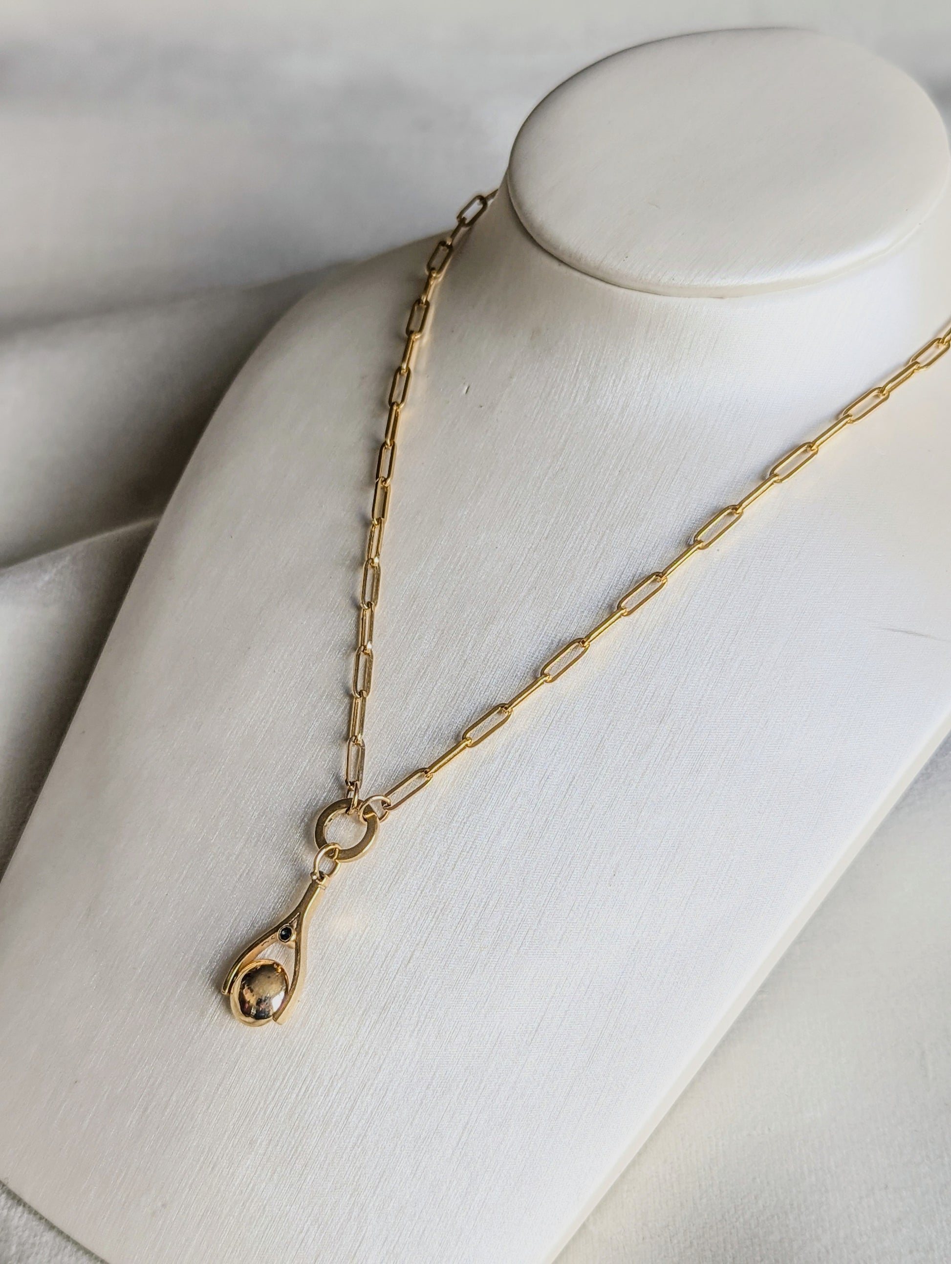 Gold paperclip necklace with a mini spinning pendant on a mannequin bust against a neutral background made by Booblinka Jewellery