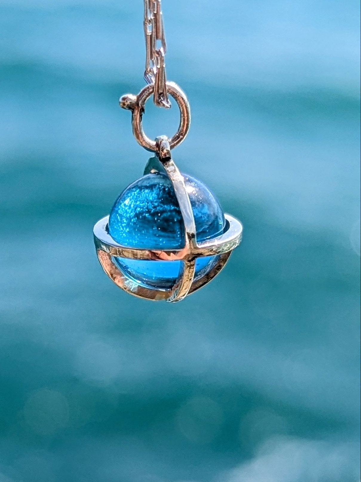 Detail of Blue topaz sphere with a shimmering ocean background made by Booblinka Jewellery