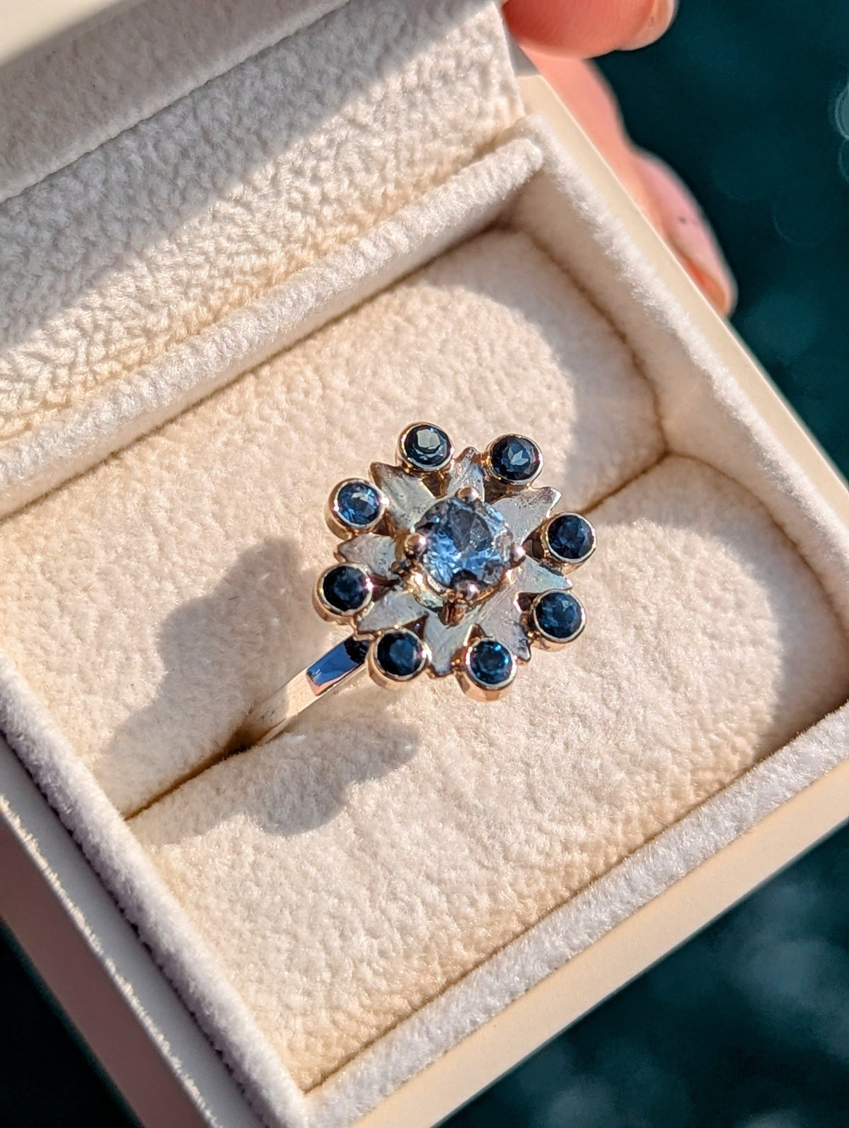 Blue topaz flower ring with gold settings displayed in a jewellery box.