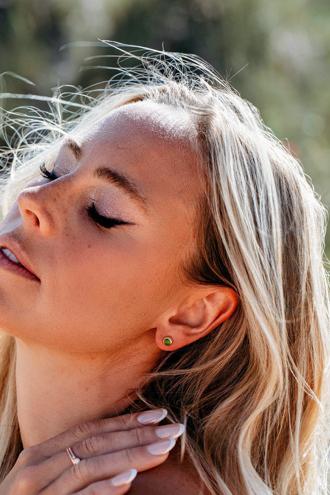 Model wearing small round green sea glass stud earrings in 9ct gold, showing their size on the ear.