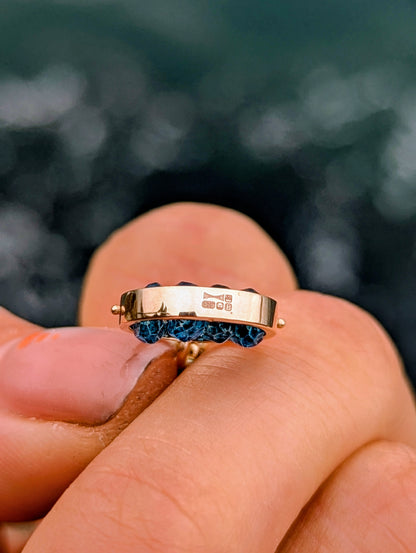 Side view of the 9ct gold HALO pendant showing its London hallmark and the four faceted blue topaz gemstones.