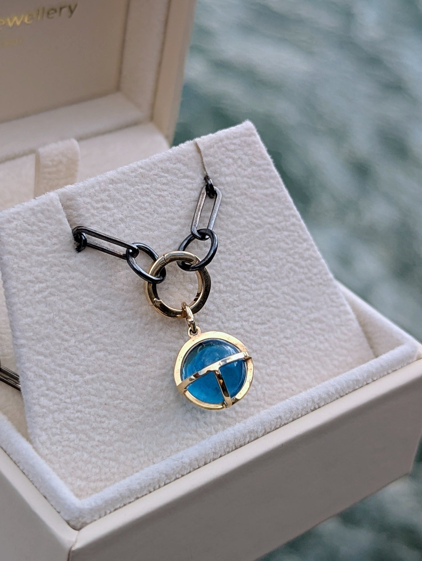 Close-up detail of a handmade Swiss Blue Topaz sphere necklace with solid 9ct gold setting and black rhodium sterling silver chain.