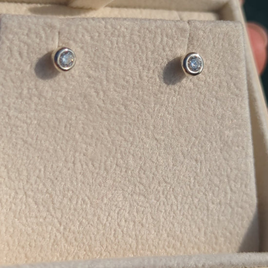 Silver stud moissanite earrings in a plush jewellery box above shimmering ocean in background made by Booblinka Jewellery