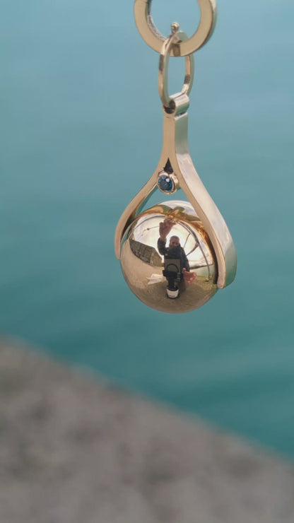 Close-up video of a handmade spinning gold necklace with blue diamonds, rotating pendant design inspired by the ocean made by Booblinka Jewellery
