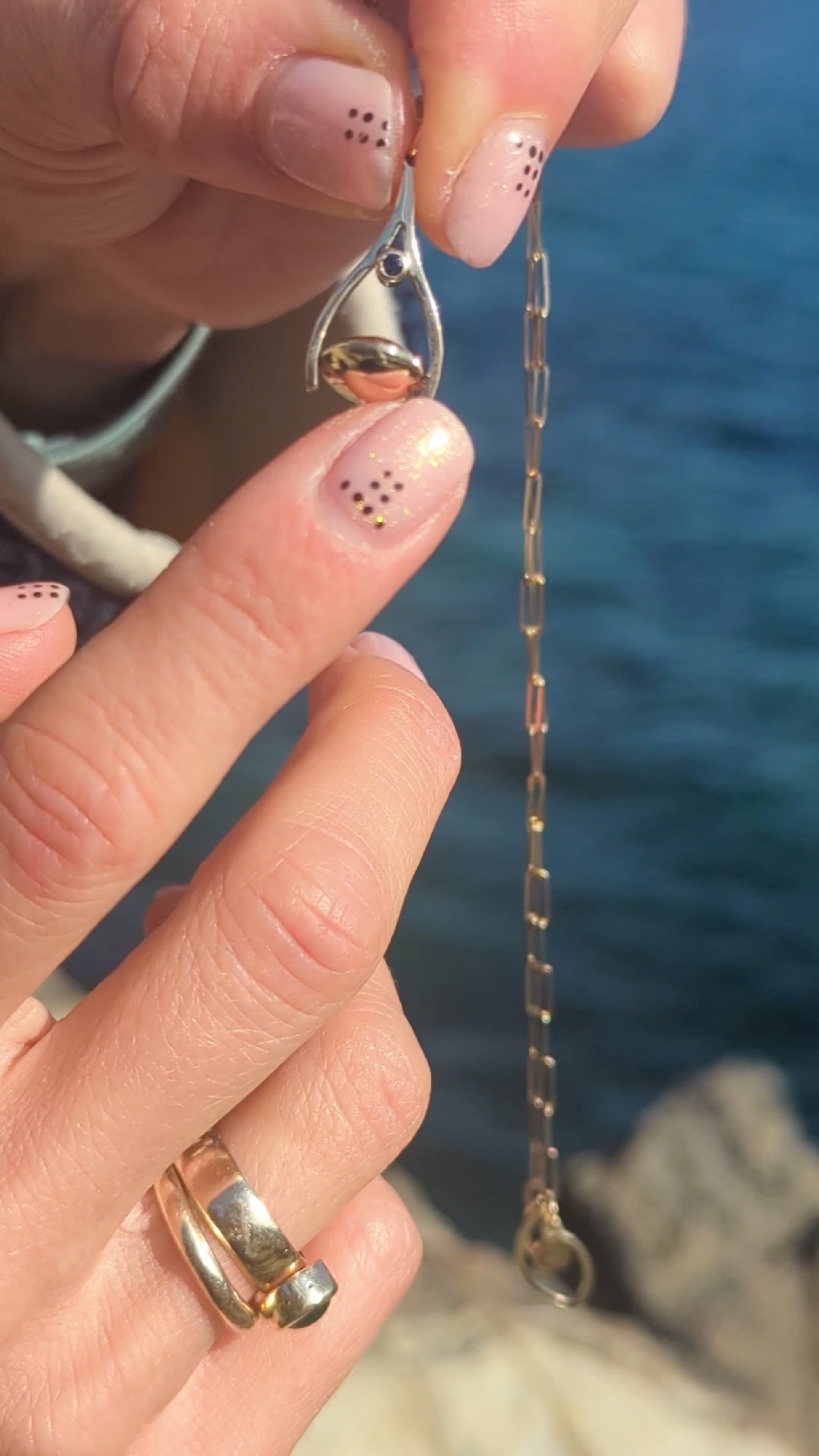 mini spinning minstrel necklace made by Booblinka Jewellery spinning above the ocean in Cornwall