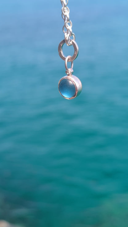 Video of the handmade blue sea glass pendant showing its rounded back designed to roll and catch the light.