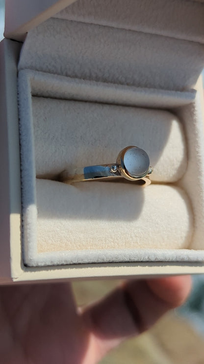 Video of Handmade Gold and silver ring with a white sea glass in a jewellery box against shimmering ocean made by Booblinka Jewellery