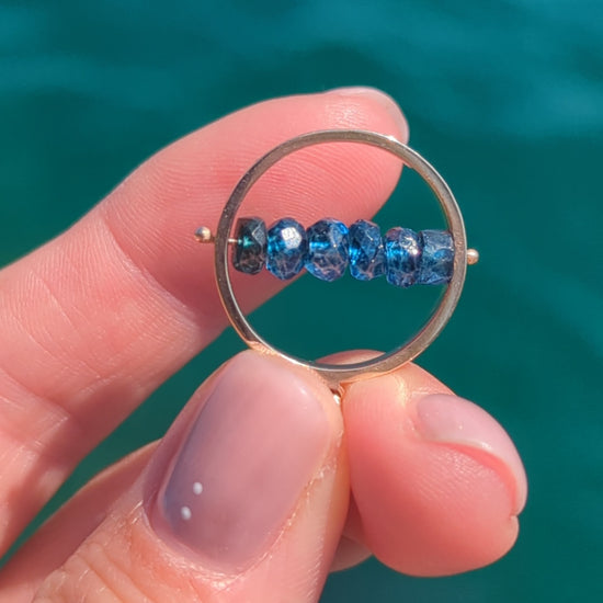 Video showing the HALO London Blue Topaz spinning necklace in solid 9ct gold as the gemstones spin.