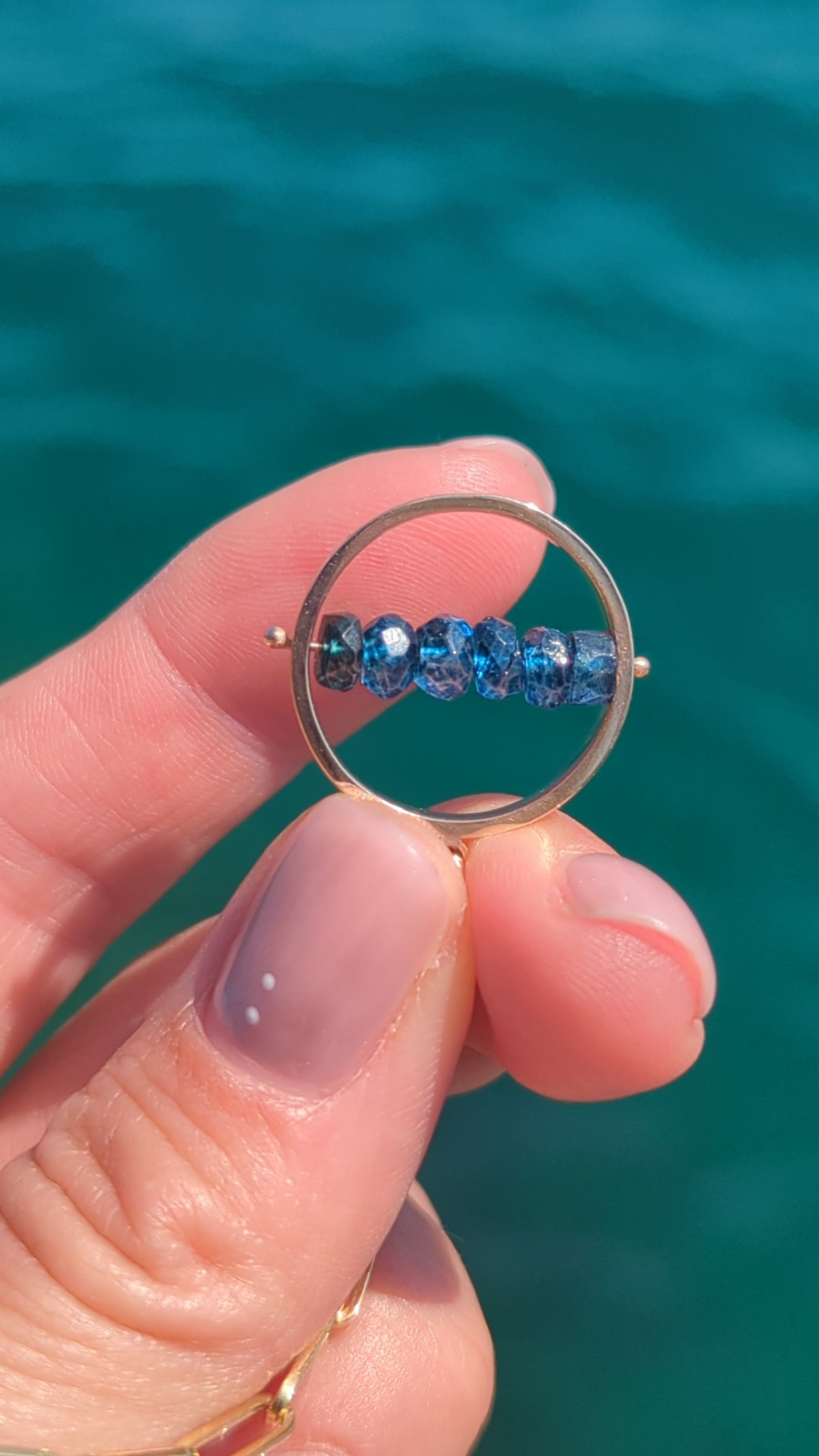 Video showing the HALO London Blue Topaz spinning necklace in solid 9ct gold as the gemstones spin.