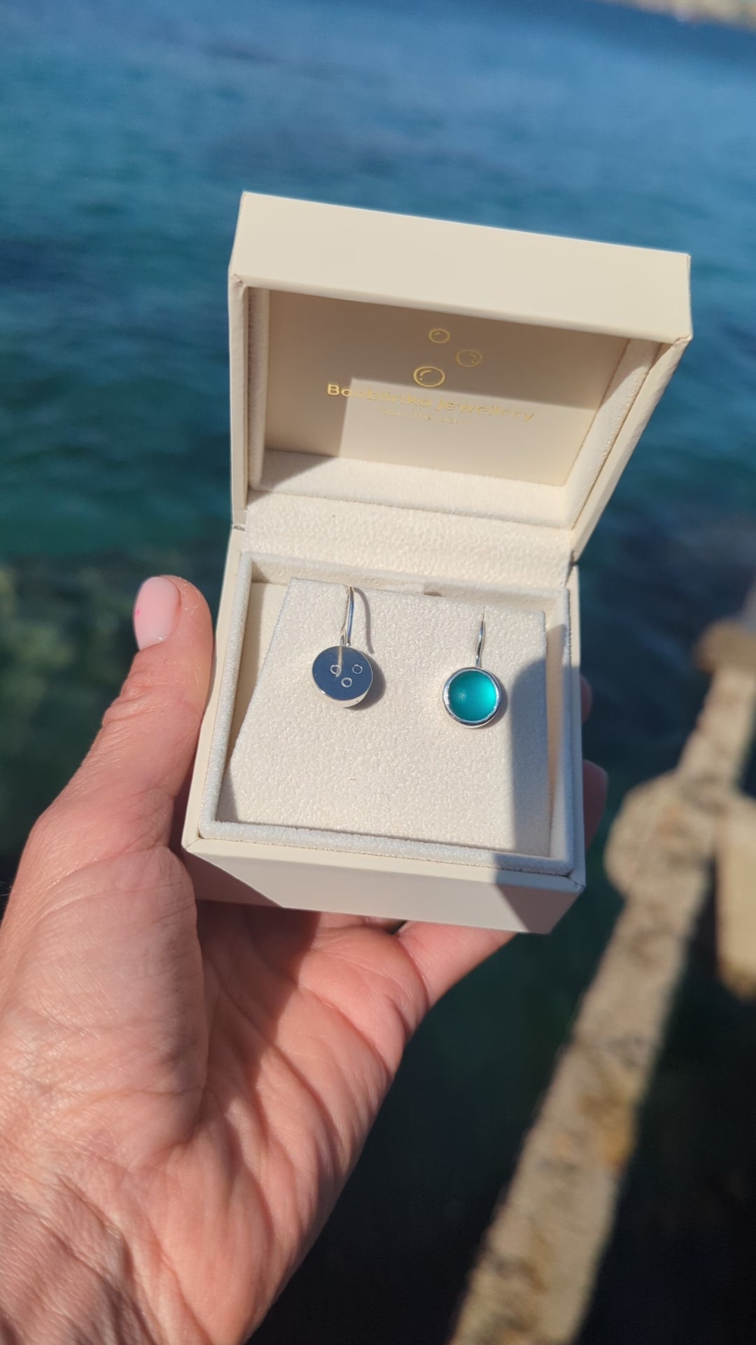 Video of Teal Sea Glass Drop Earrings in Sterling Silver in a jewellery box above the ocean made by Booblinka Jewellery