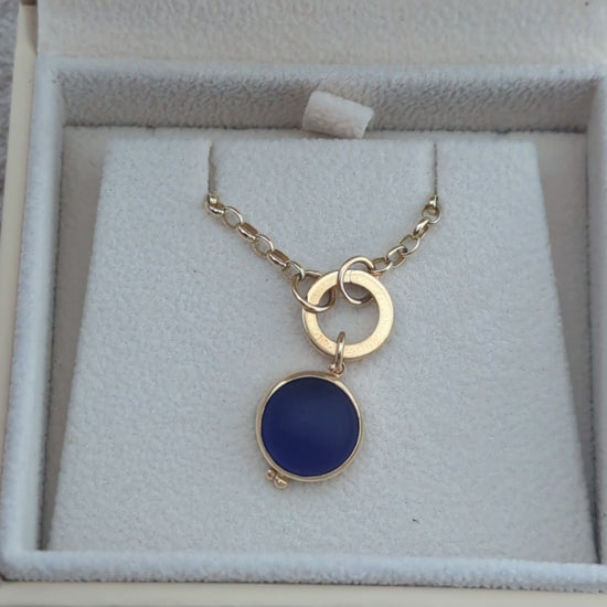 Video showing a round blue sea glass pendant in solid 9ct gold with a hinged gold charm holder and gold chain in a jewellery box.