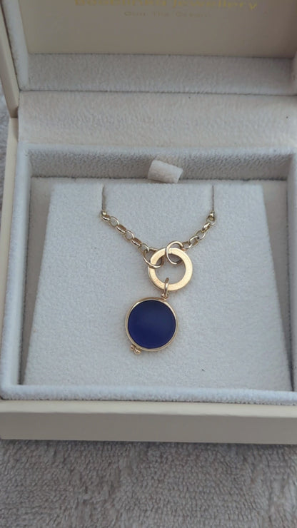 Video showing a round blue sea glass pendant in solid 9ct gold with a hinged gold charm holder and gold chain in a jewellery box.