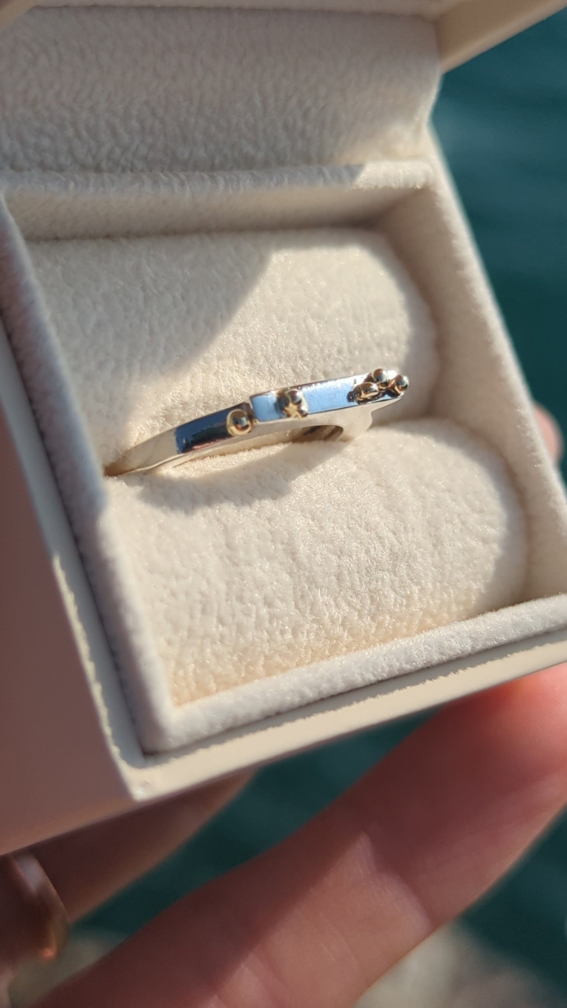 Contemporary Silver Ring with 9ct Gold Granules in an ivory jewellery box above the ocean made by Booblinka jewellery