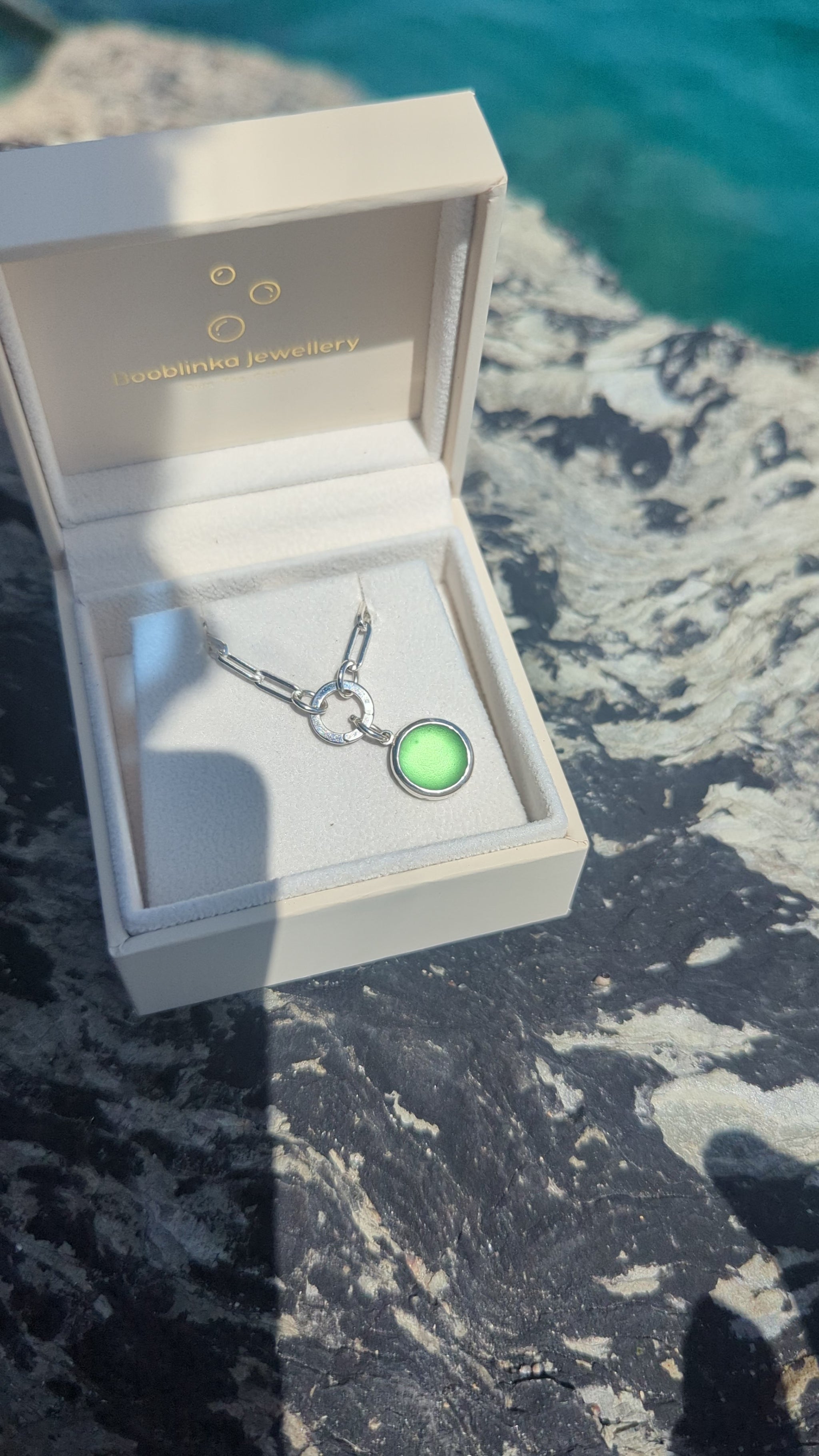 Video showing how to open the hinged charm holder to remove the green sea glass pendant from the sterling silver paperclip chain.