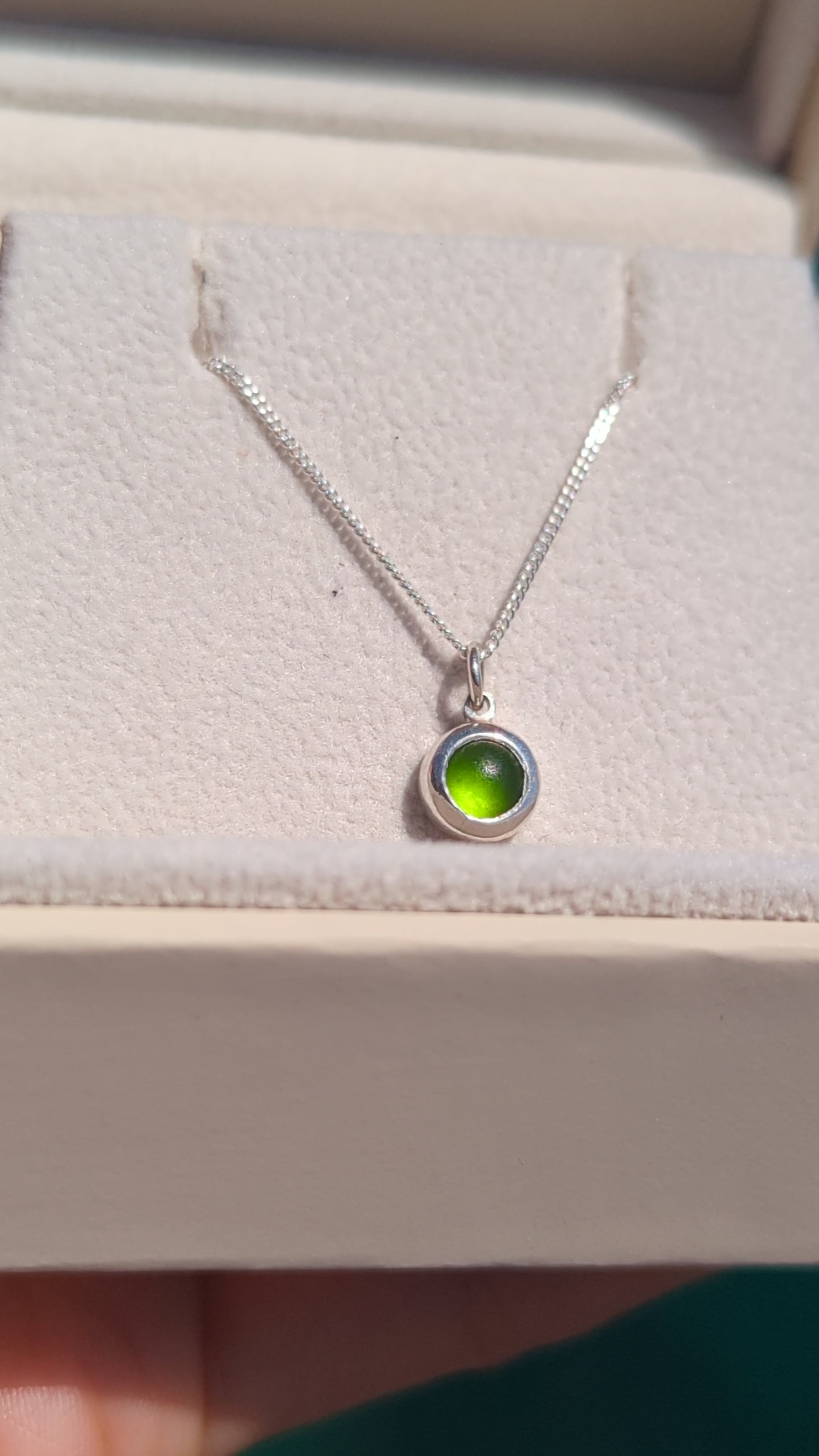 Video showing a tiny genuine green sea glass necklace in sterling silver from different angles and how it catches the light.
