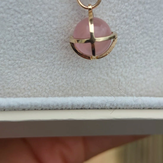 Video of spherical rose quartz set in solid gold cage in a jewellery box