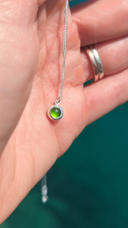 Video showing a tiny genuine green sea glass necklace in sterling silver held in the hand to show its size and colour.