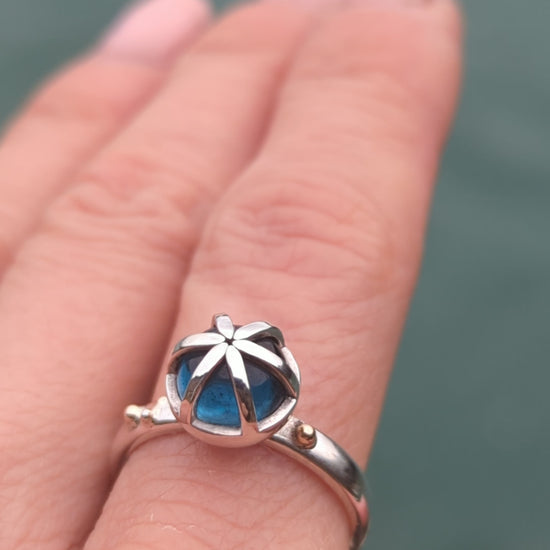 Video of a statement silver ring on a hand with round London blue topaz in a cage with gold granules made by Booblinka Jewellery.