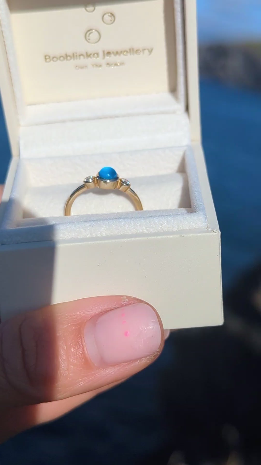 Gold engagement ring with a blue sea glass and two ocean diamonds in an ivory jewellery box made by Booblinka Jewellery