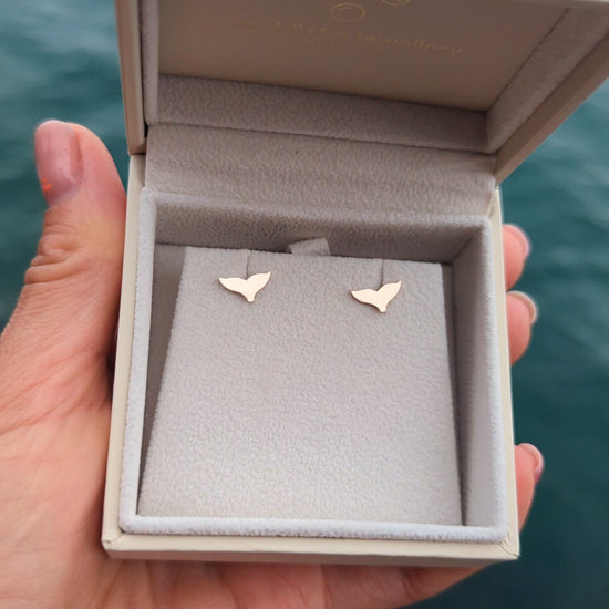 video of 9ct rose gold mermaid tail earrings in a jewellery box held above the ocean