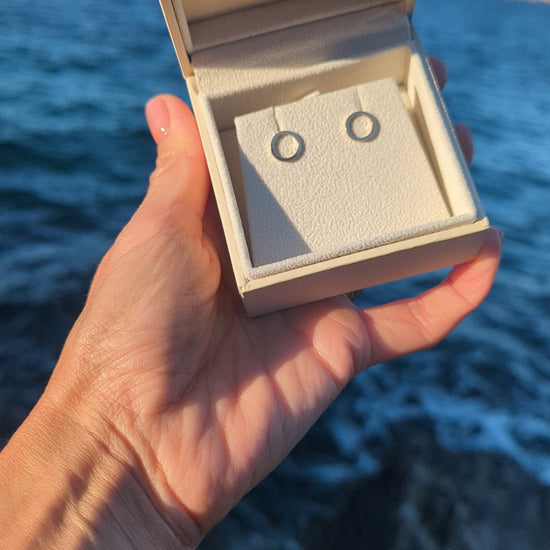 Video of  handmade 9ct gold circle stud earrings in a Booblinka Jewellery box held in hand above the ocean.