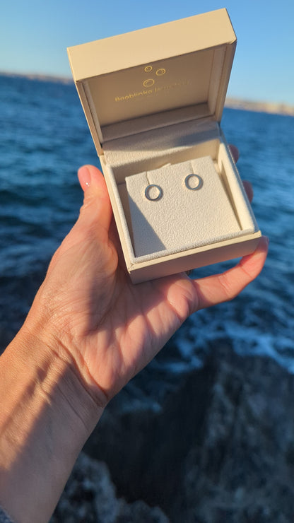 Video of  handmade 9ct gold circle stud earrings in a Booblinka Jewellery box held in hand above the ocean.