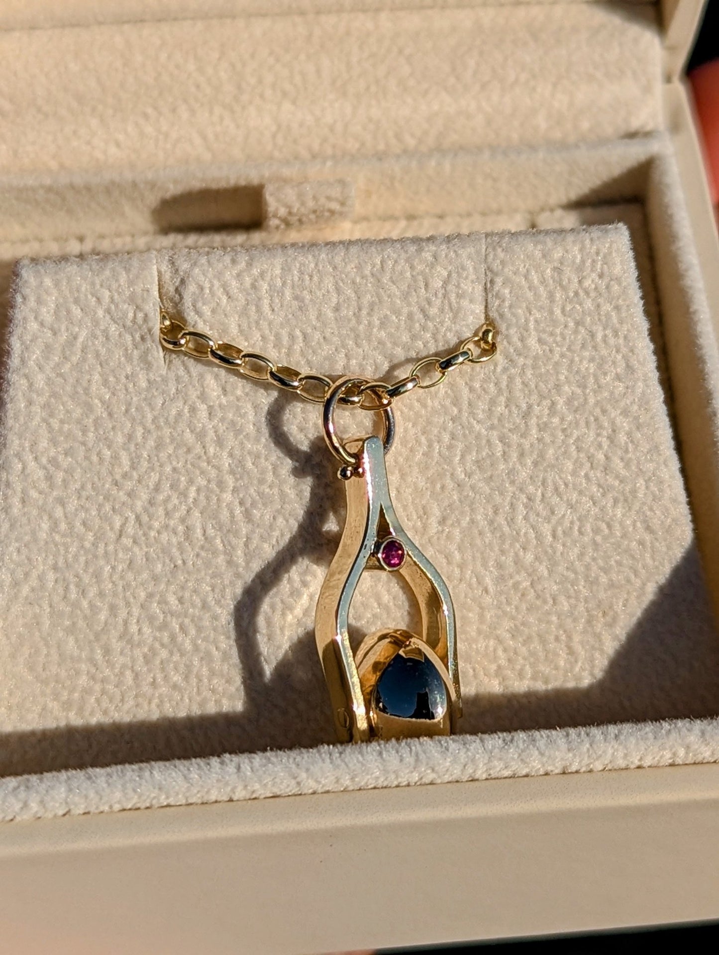 Gold Spinning Moon Necklace with pink tourmalines made by Booblinka Jewellery in an ivory plush jewellery box glowing in the sunshine