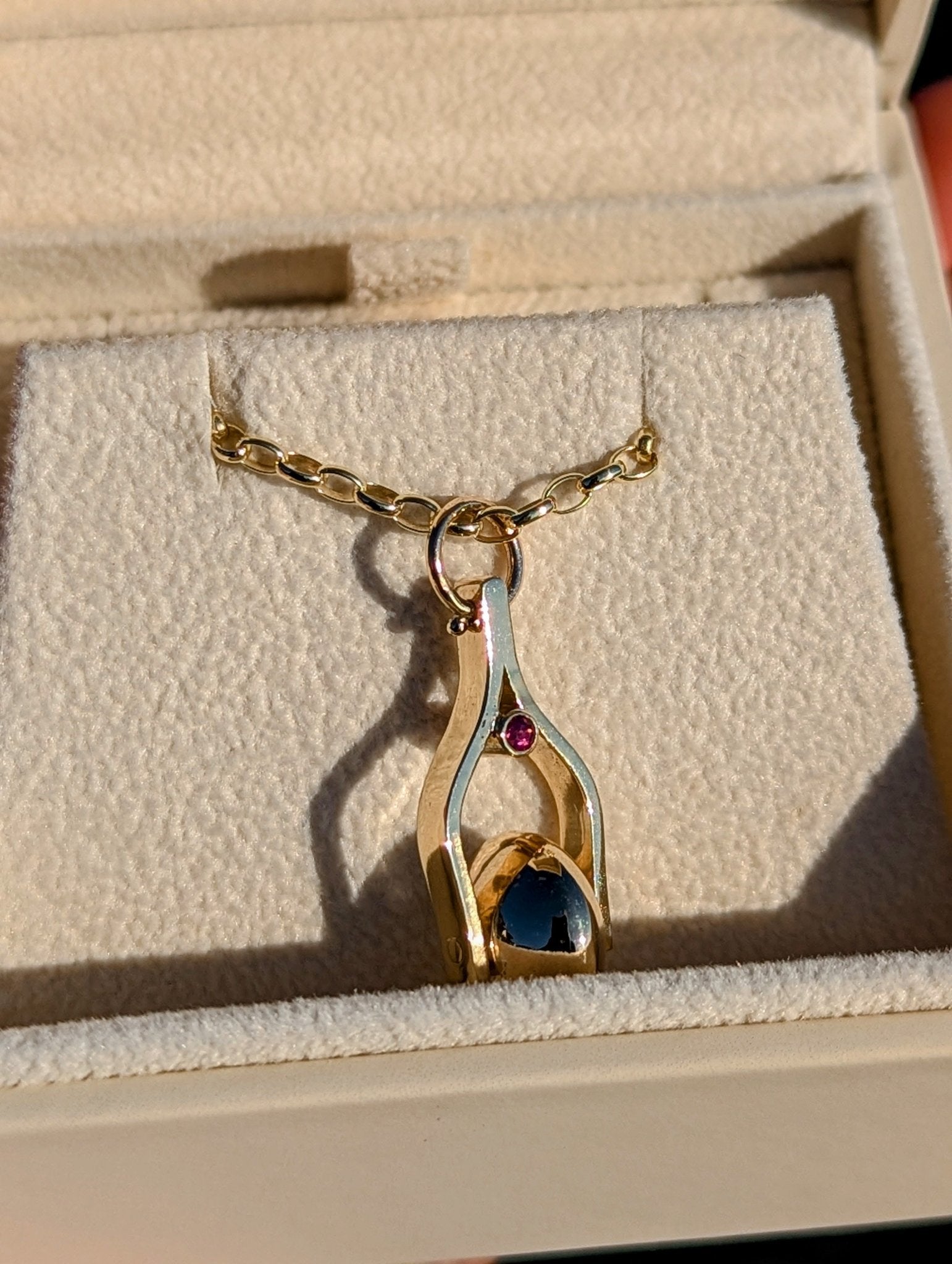 Gold Spinning Moon Necklace with pink tourmalines made by Booblinka Jewellery in an ivory plush jewellery box glowing in the sunshine