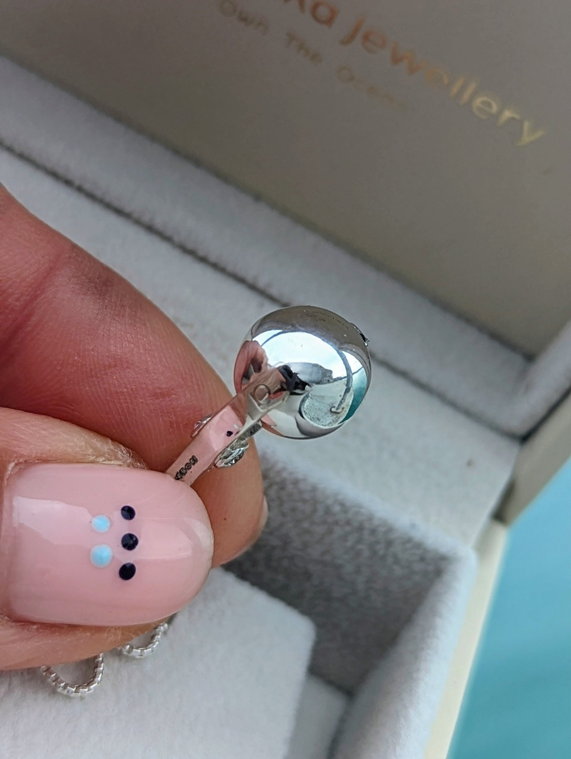Close-up of handmade polished spinning silver ball  with moissanites in hand 