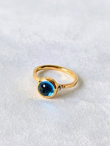Swiss Blue Topaz Cabochon Gold Ring with diamond from Drop of the Ocean Collection on white velvet made by Booblinka Jewellery