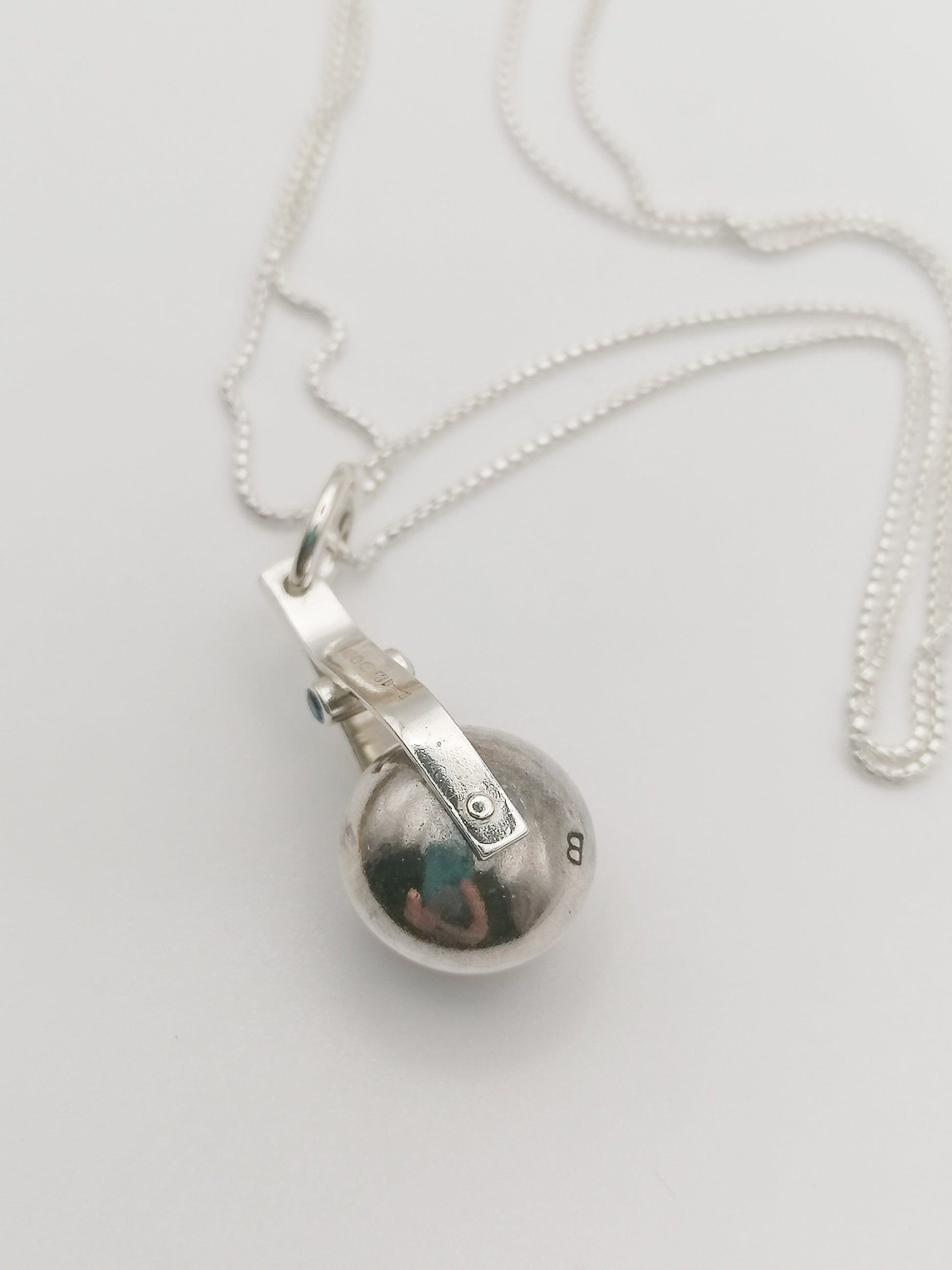 Shot of the spinning moon necklace in sterling silver with a blue gemstone, showcasing its unique design as seen in 'Playing Nice' by Booblinka Jewellery