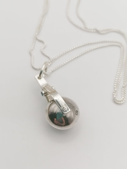 Shot of the spinning moon necklace in sterling silver with a blue gemstone, showcasing its unique design as seen in 'Playing Nice' by Booblinka Jewellery
