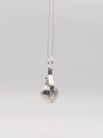 Shot of the spinning moon necklace in sterling silver with a blue gemstone, showcasing its unique design as seen in 'Playing Nice' by Booblinka Jewellery
