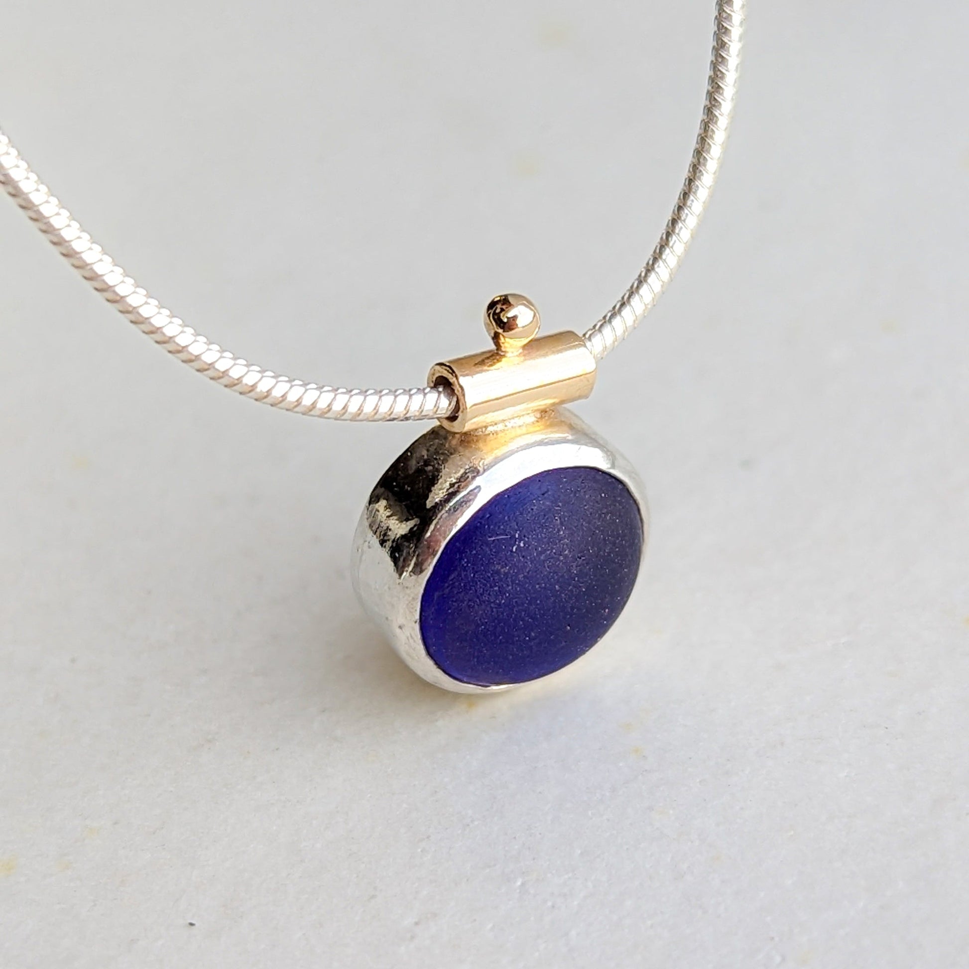 Silver and gold snake necklace with deep blue round sea glass
